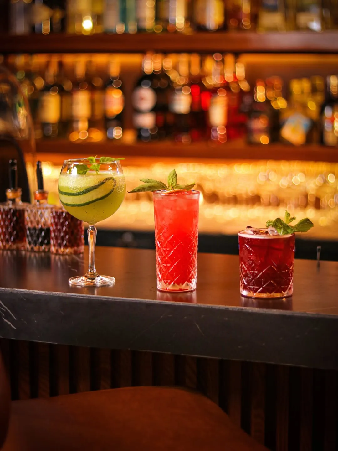 Three colourful cocktails lined up at the bar