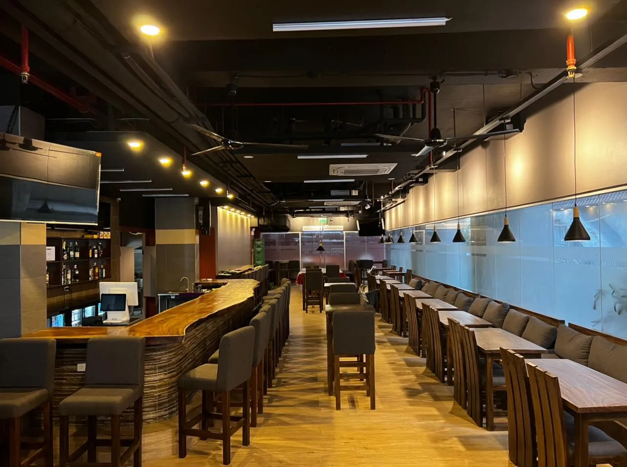 Long wooden bar and rows of tables inside the sports bar