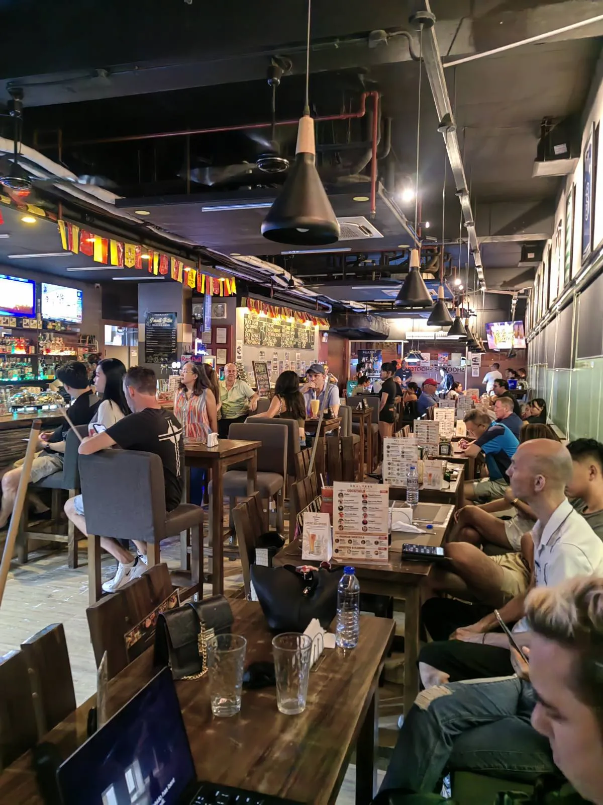 Crowded sports bar with table seating and televisions along the counter