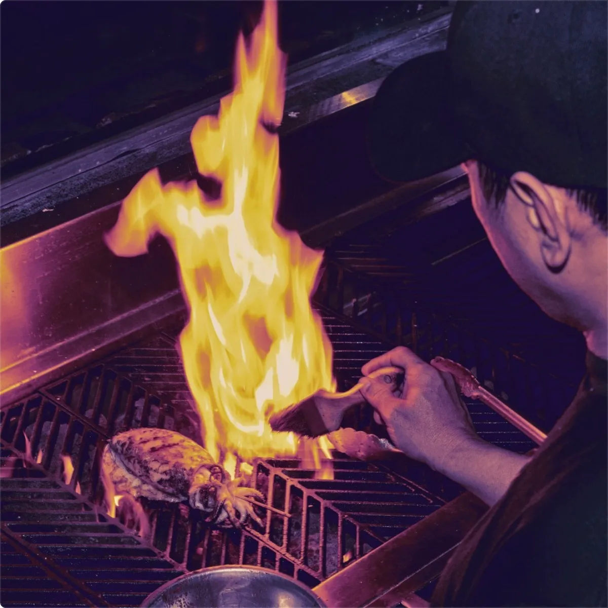 Squid being flame-grilled over the kitchen grate