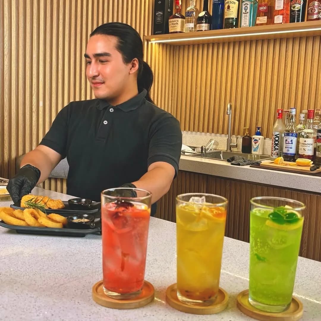 Three colorful non-alcoholic drinks lined up on the bar.