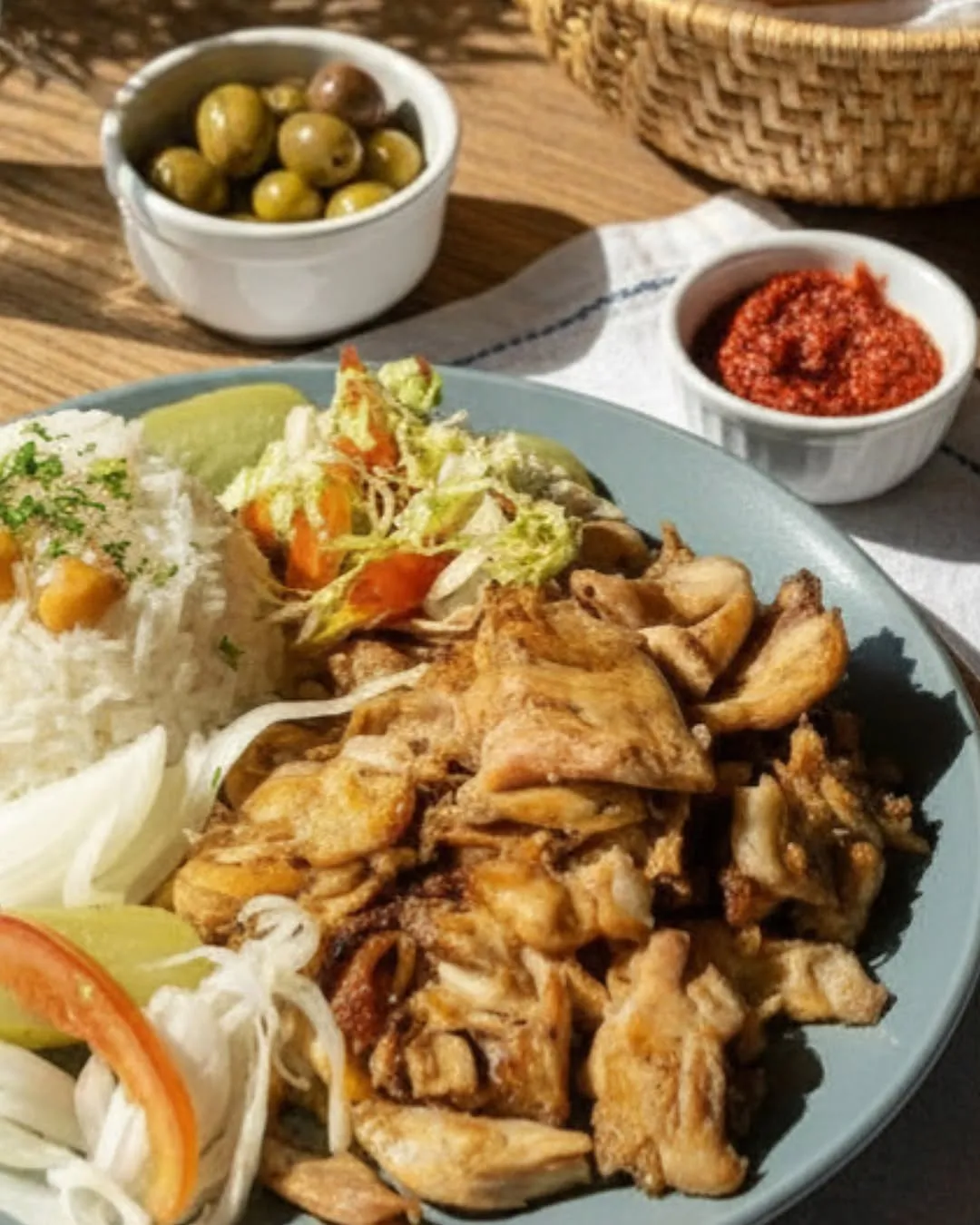 Sliced chicken döner with rice, salad and small side dishes.