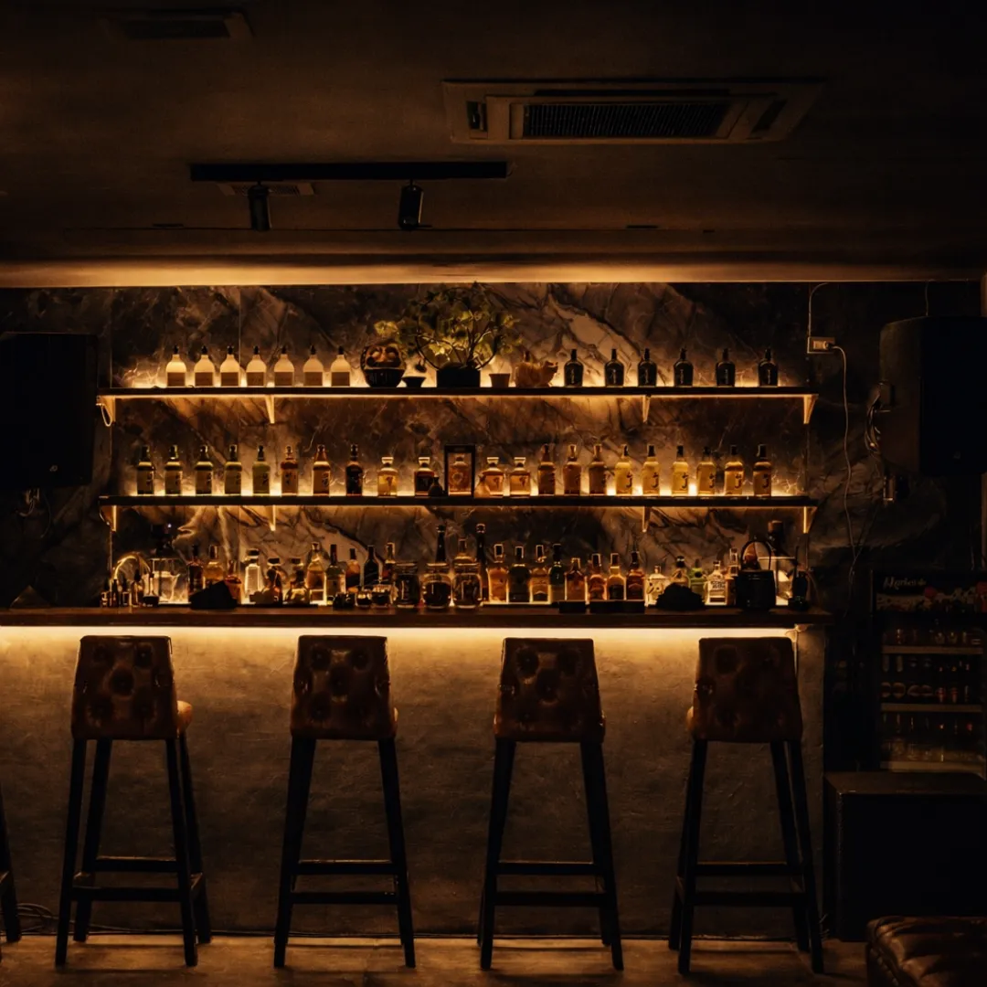 Backlit bottle wall with four bar stools