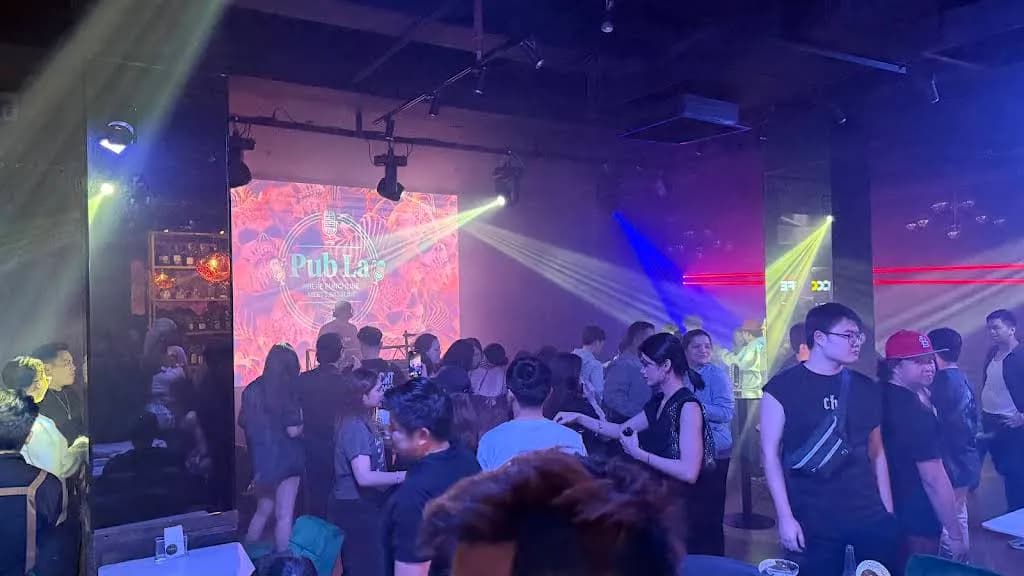 Crowded dance floor beneath coloured stage lights and an illuminated screen