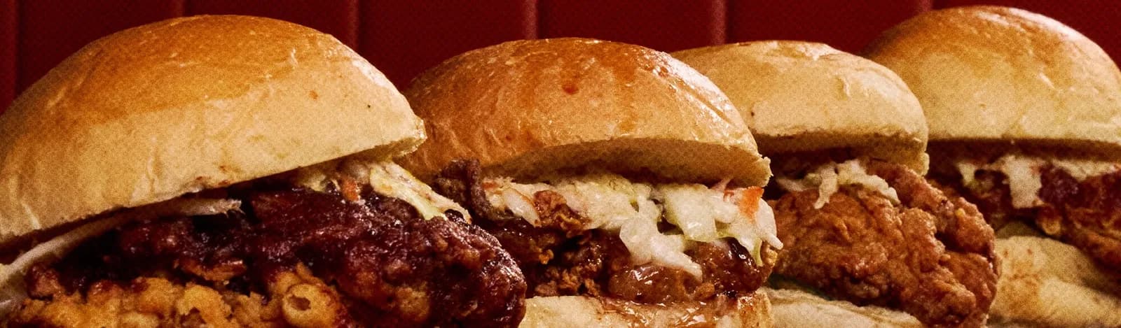 Four fried chicken sandwiches in a row, with slaw and glazed fillets