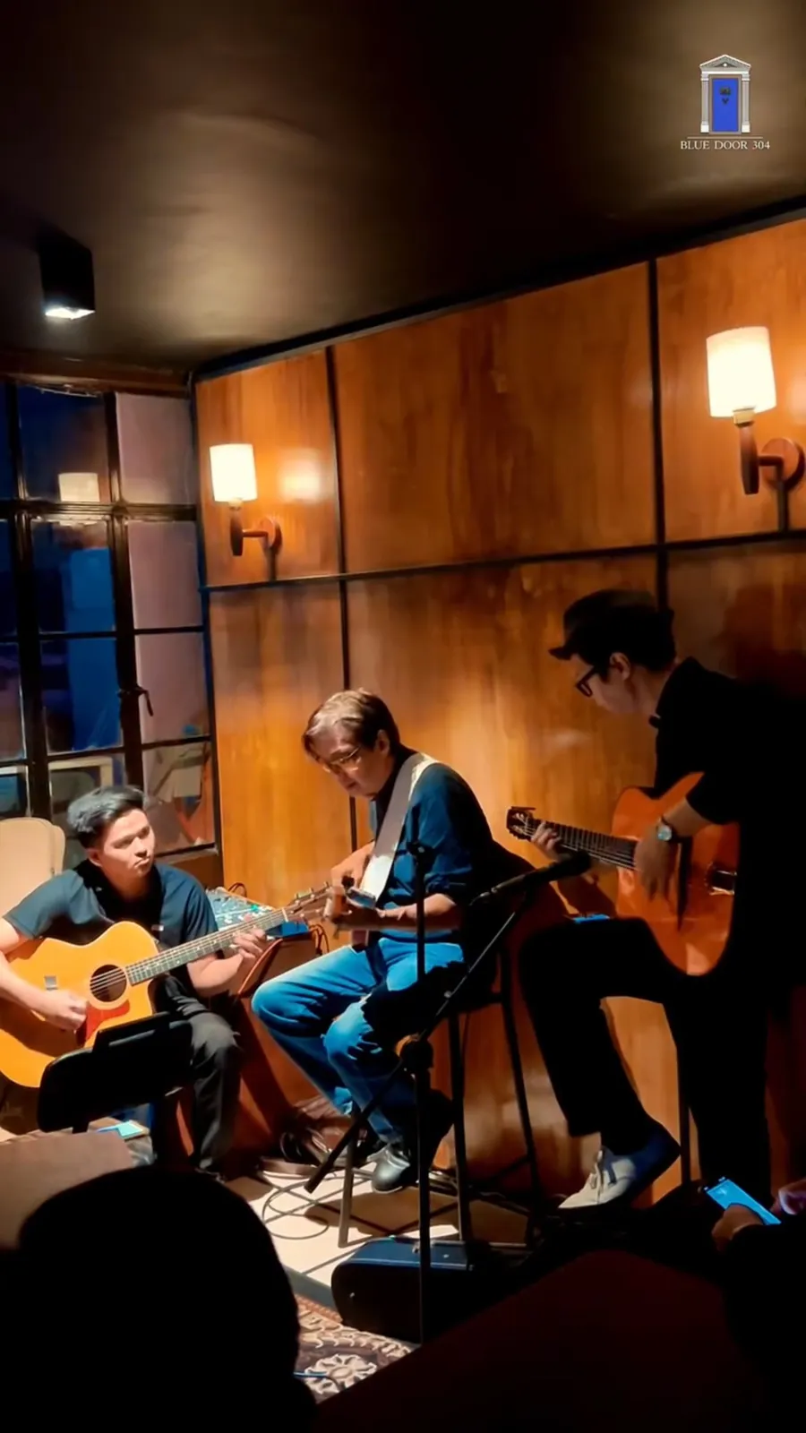 An acoustic trio playing in the wood-panelled room.