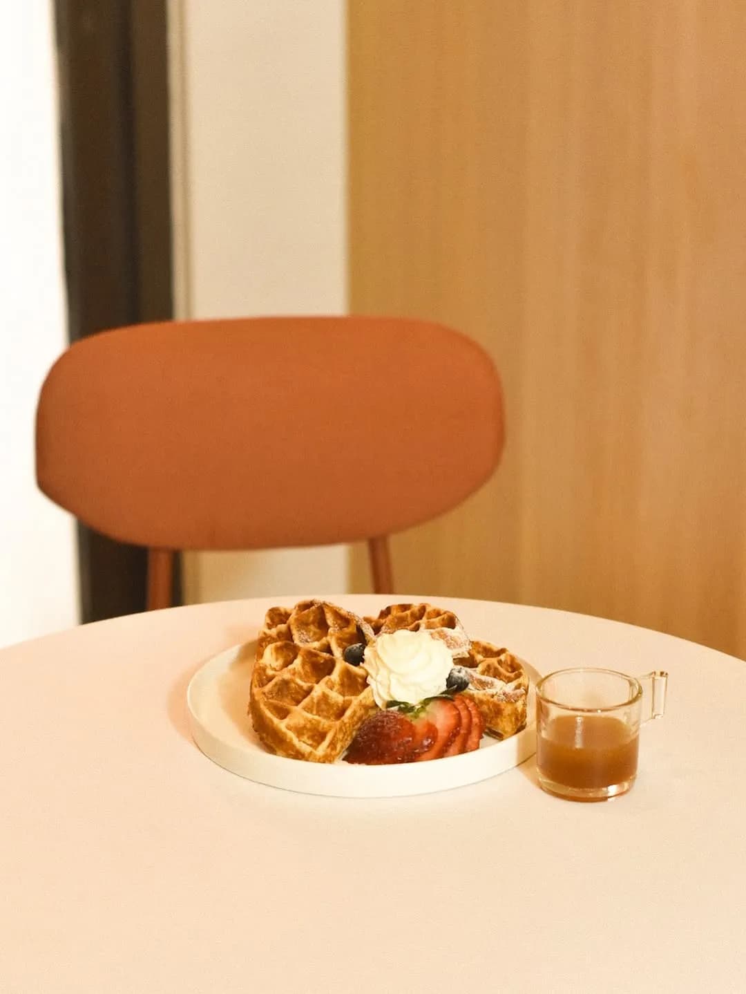 Buttermilk waffles, whipped cream and syrup on a café table