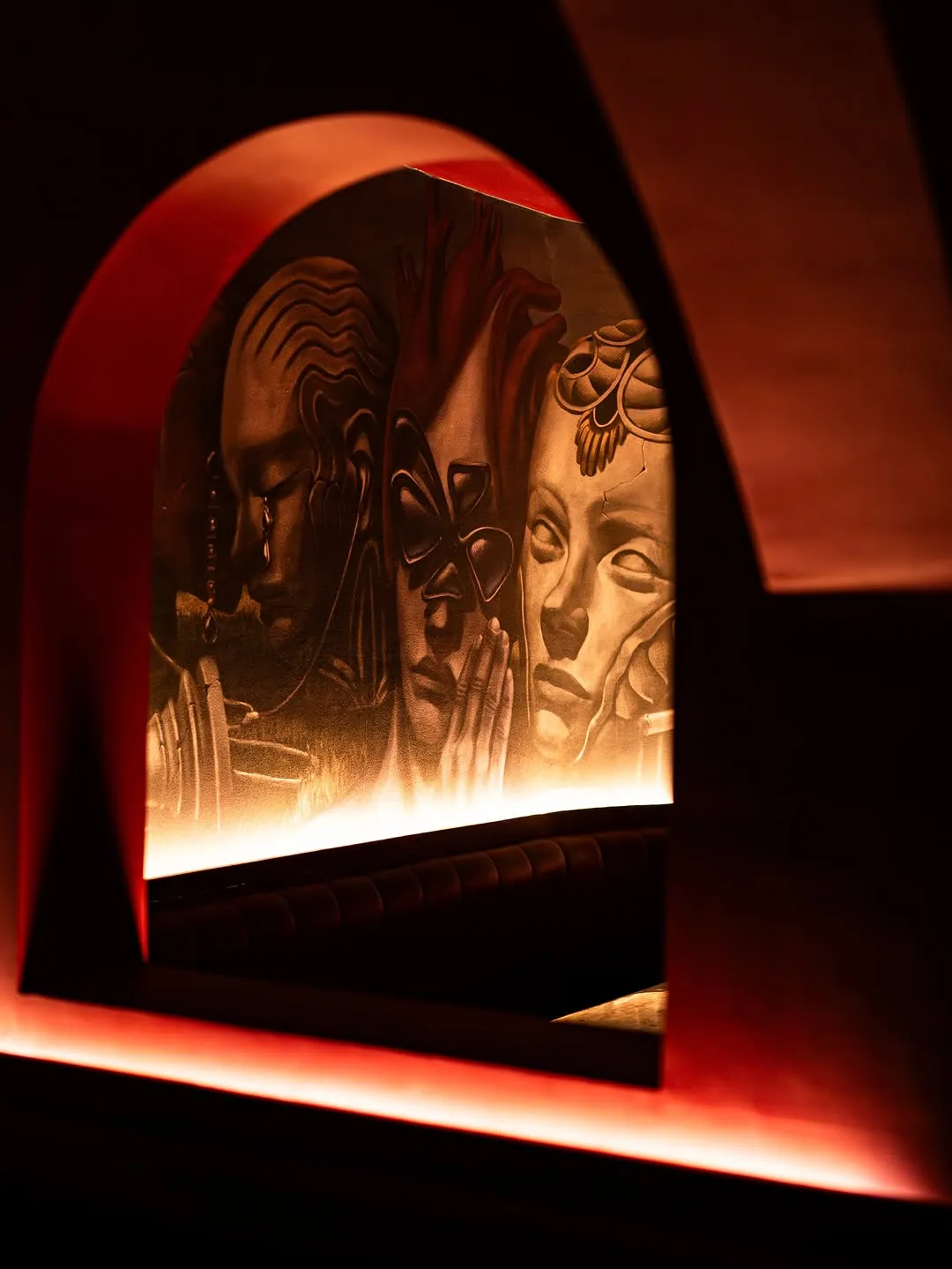 A lit cat artwork inside the red-toned cocktail bar.