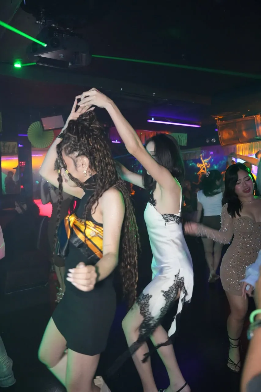 Crowded dance floor under green lasers and neon lighting.
