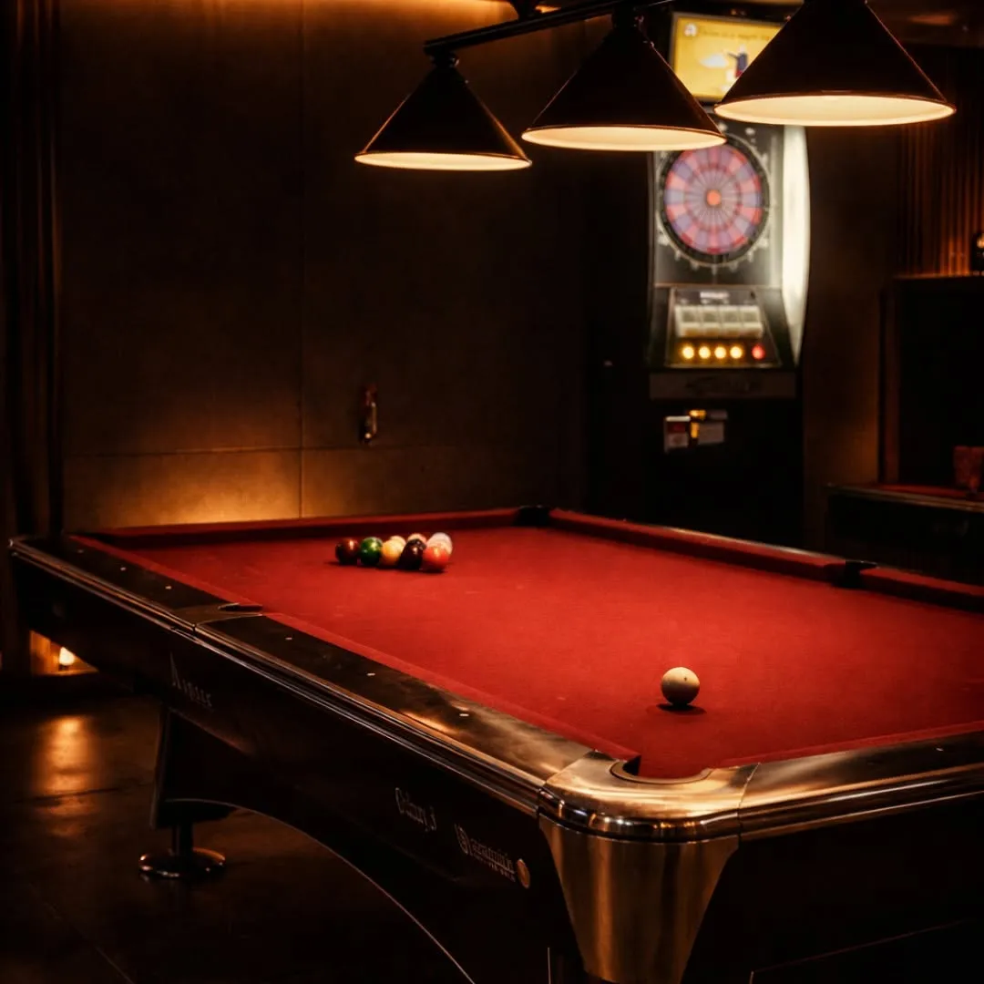 Red-felt billiards table under warm hanging lamps