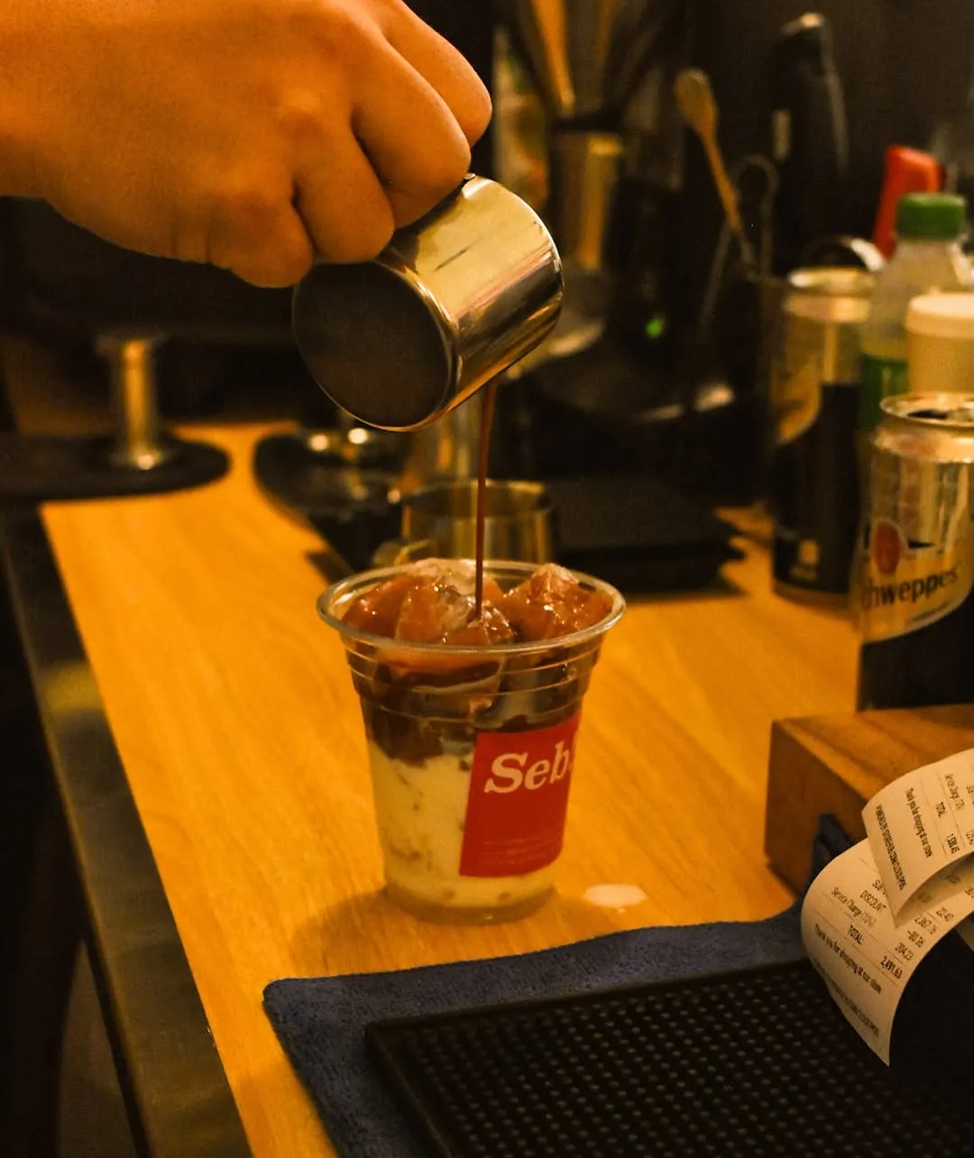 Dark mocha being poured over ice at the counter