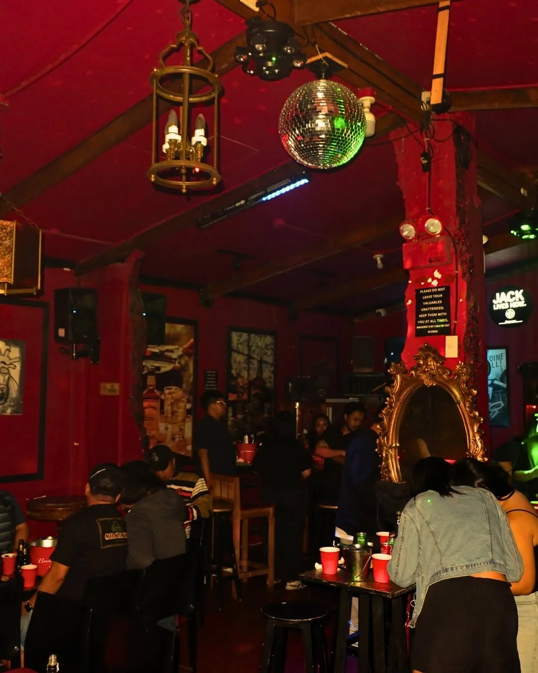 Red-lit bar room with customers seated around the counter