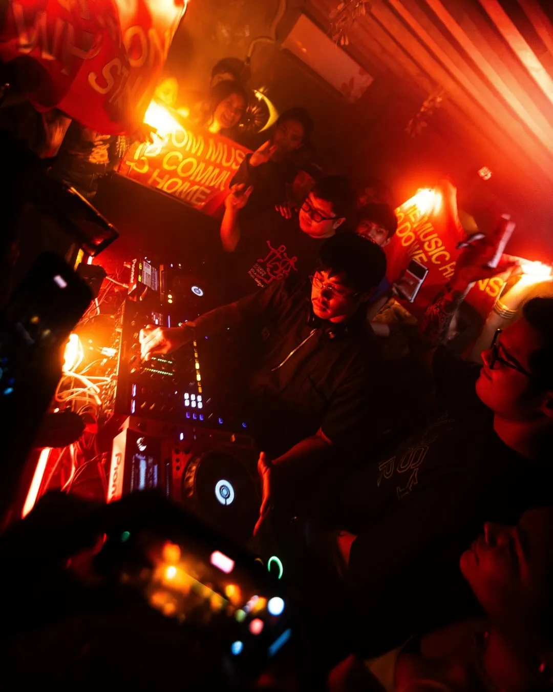 A DJ at the decks surrounded by the crowd inside Xin Chào.