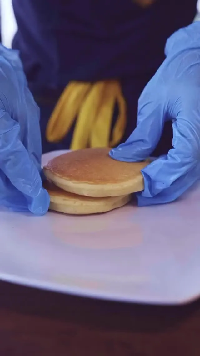 Cook assembling a stack of plain pancakes