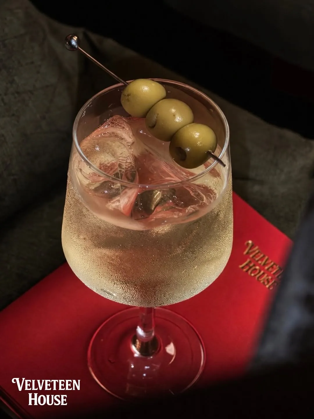 Dirty martini with three green olives on a red menu