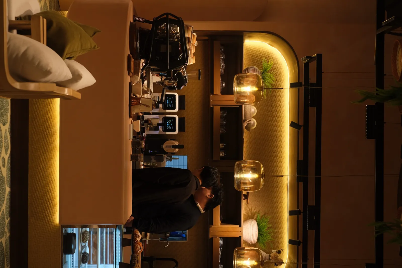 Amber-lit coffee bar with espresso machines and pastry display