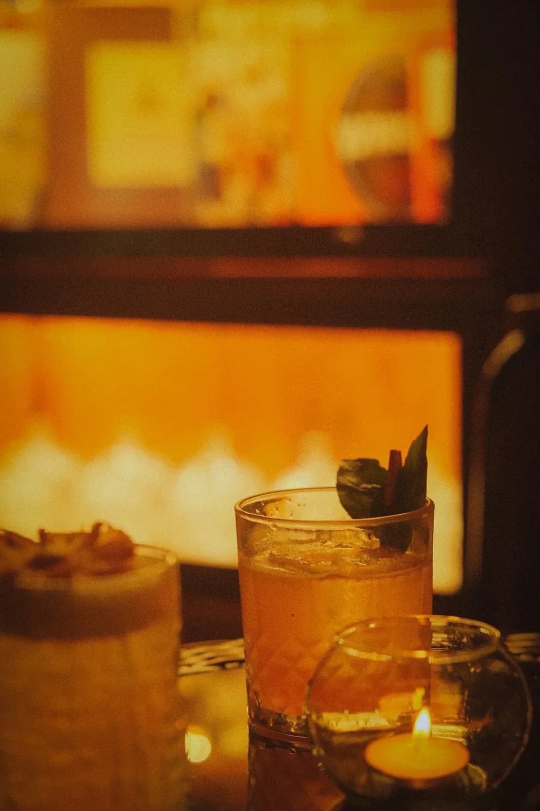Two amber cocktails beside a candle in the low-lit bar