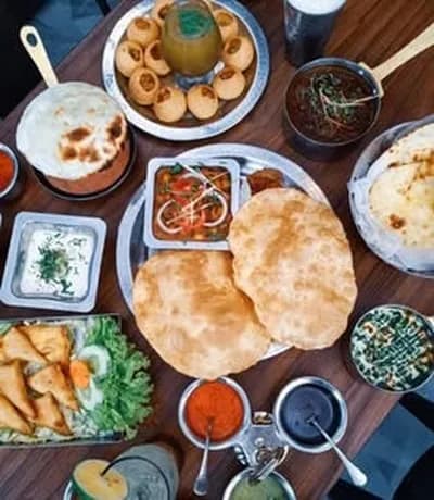 Overhead spread of naan, samosas, curries and dipping sauces