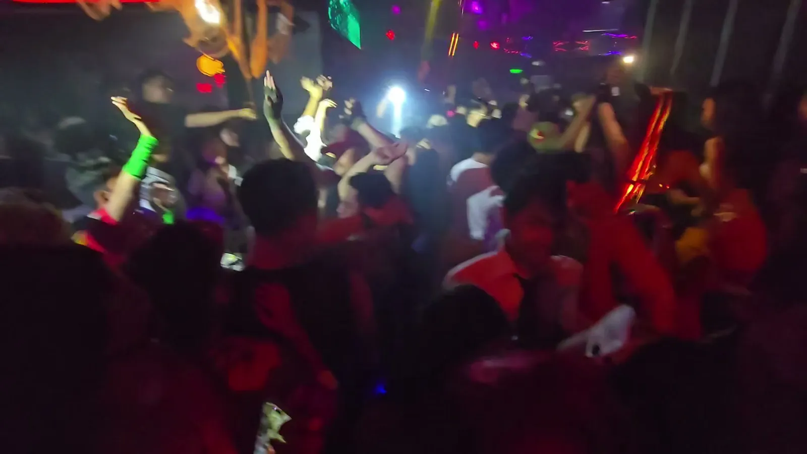 Crowded nightclub dance floor lit red and green