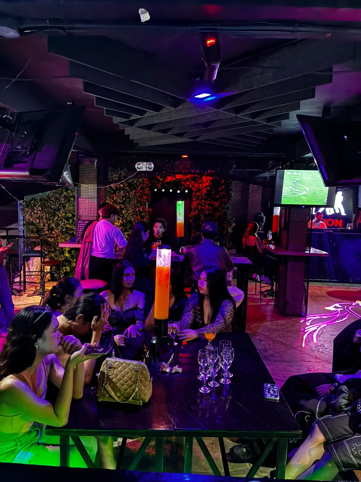 Groups seated around long tables under colored lights inside the sports bar