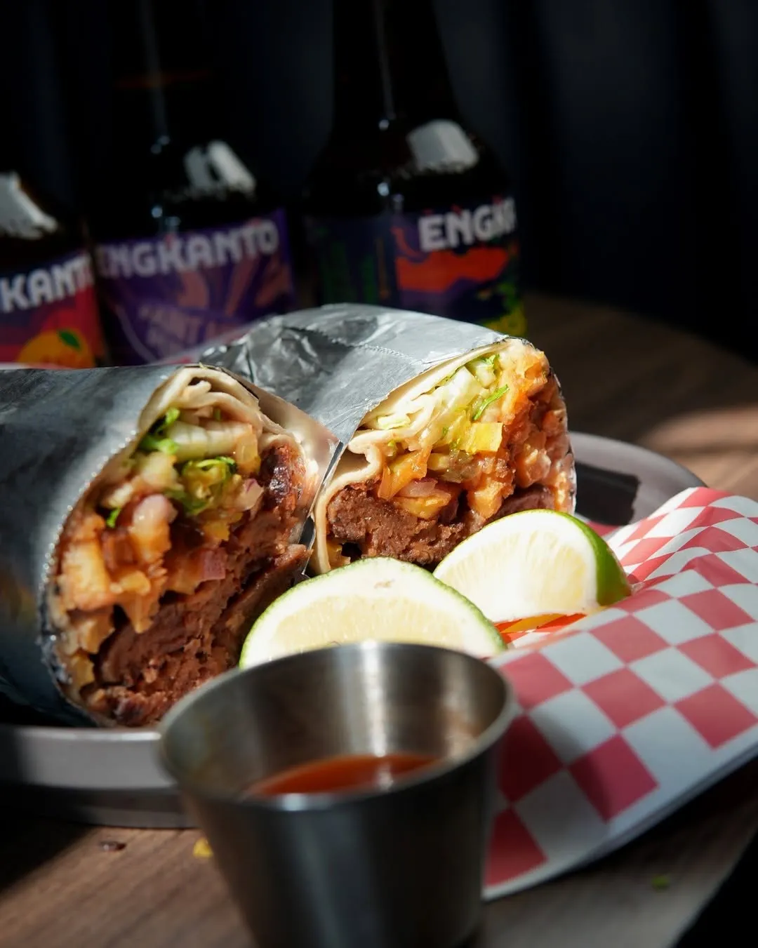 Two filled burritos with lime and dipping sauce