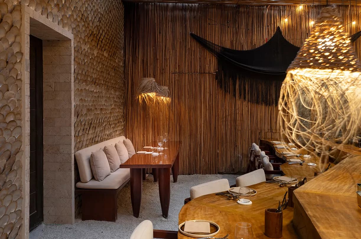 Warmly lit dining room with bamboo walls, shell-lined surfaces and a long wooden counter.