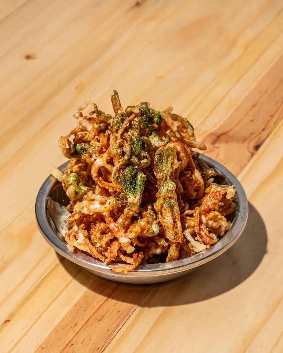 Noodle bowl topped with fried chicken and herbs