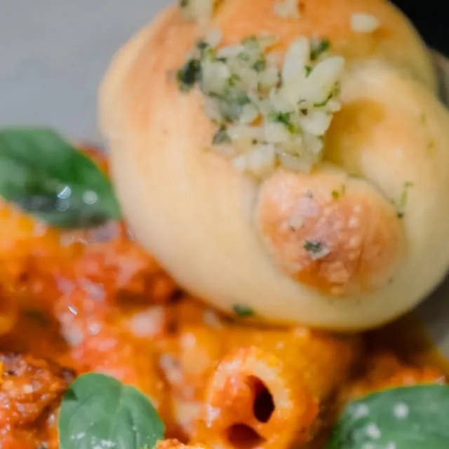 Vodka-sauce pasta with a garlic knot and basil.