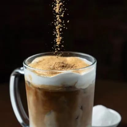 Iced coffee topped with cream and a dusting of spice.