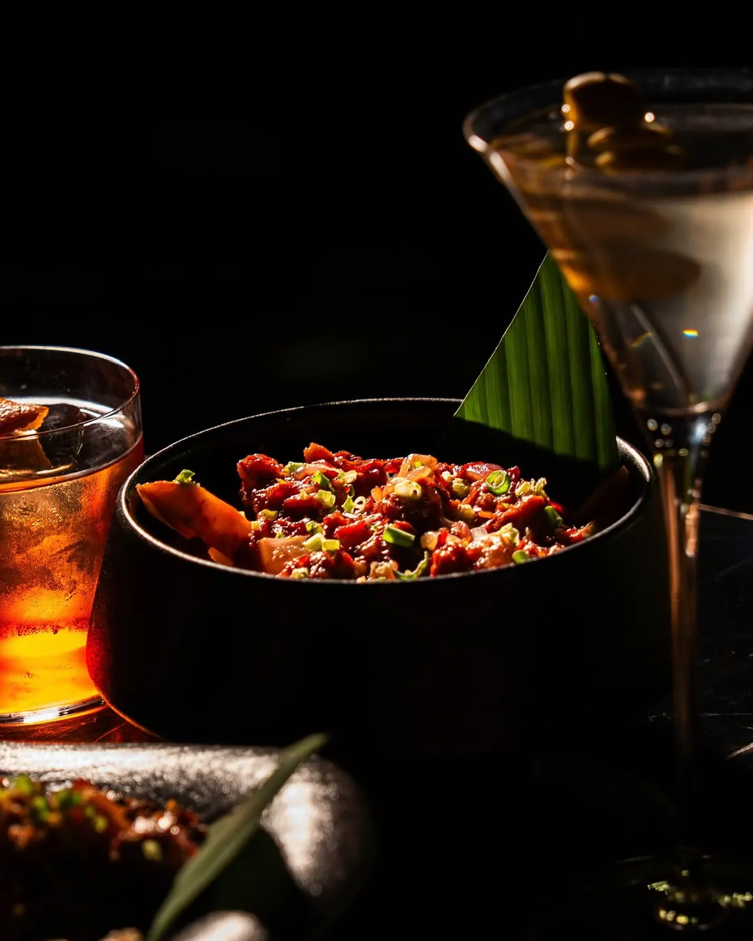 Bowl of corned beef fries beside cocktails on the bar