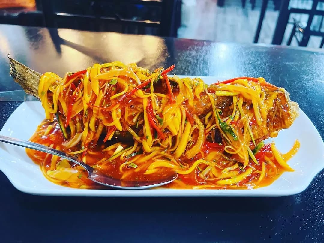 Lapu-lapu in mango sauce on a black plate