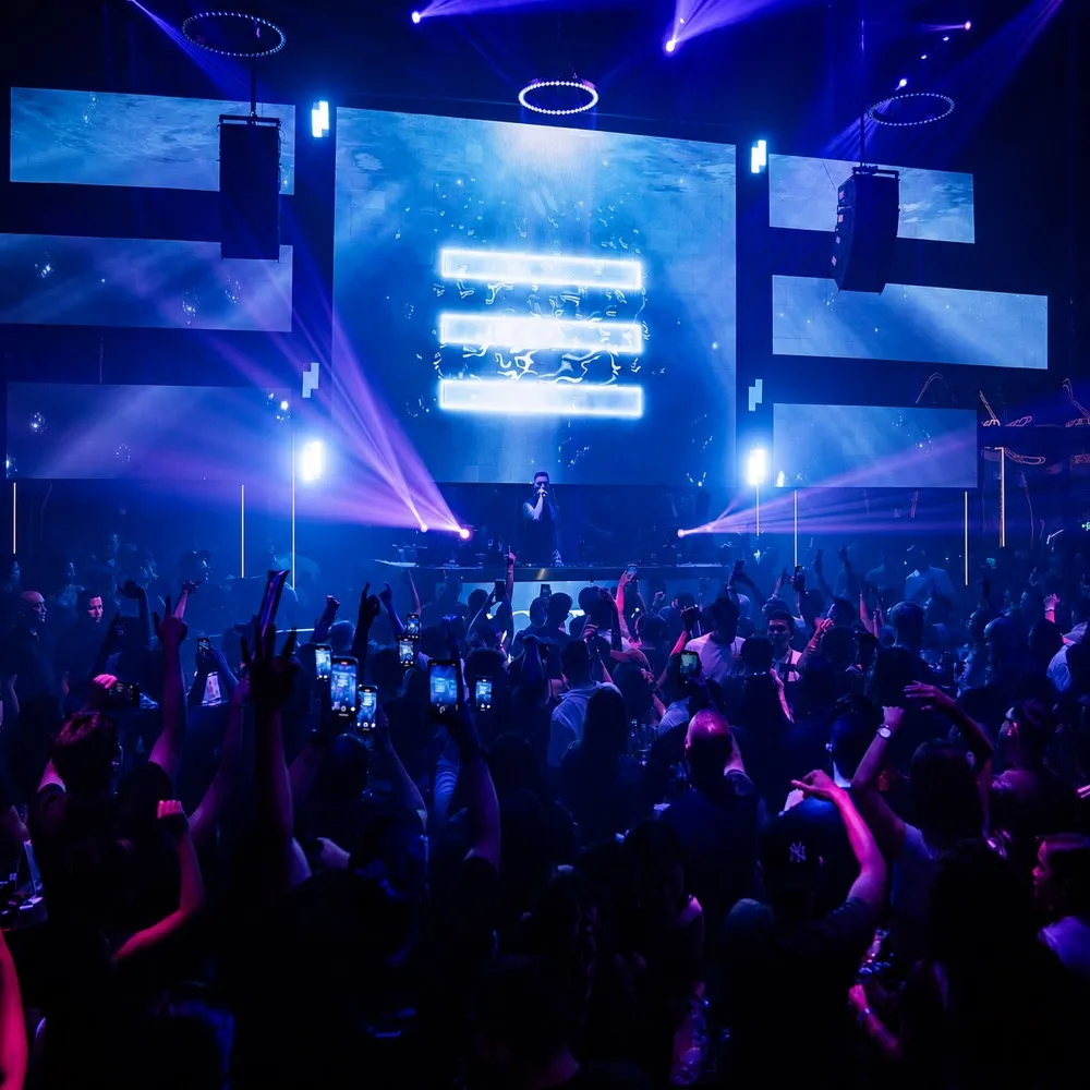 Octopus nightclub dance floor facing a wall of blue LED screens and stage lights.