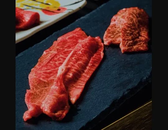 Three marbled raw Wagyu cuts on a black stone platter