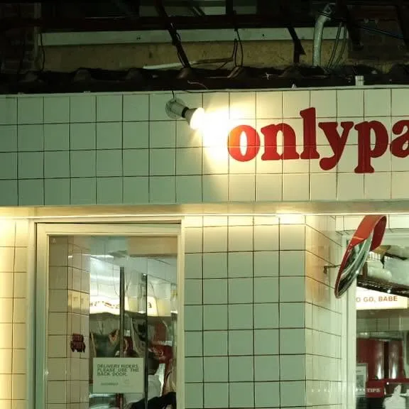 White-tiled Onlypans storefront with its red sign and service window