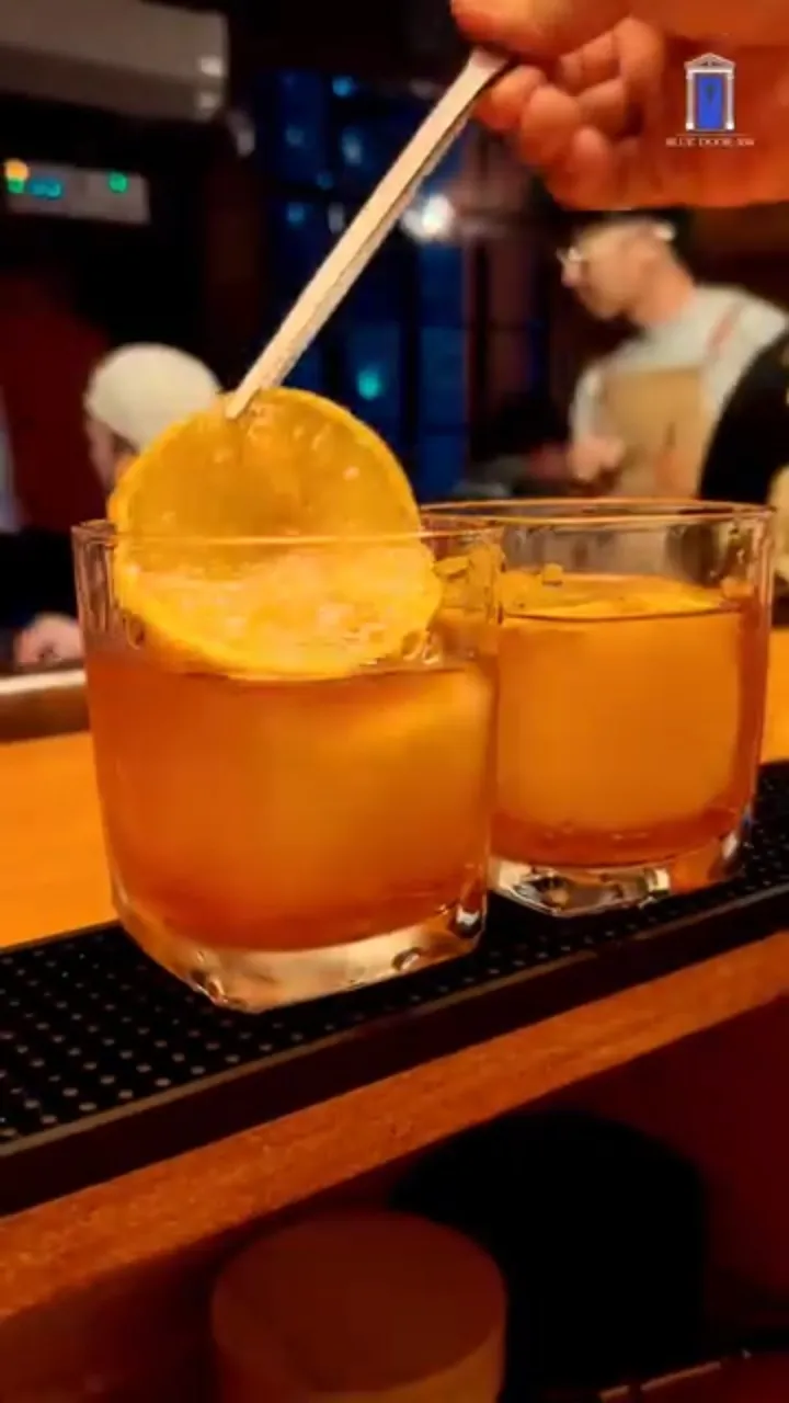 Two amber cocktails on the wood bar.
