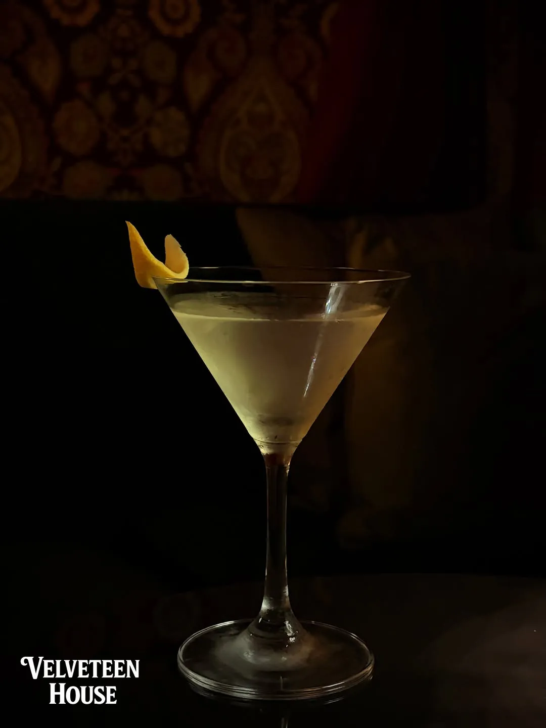 Martini with a lemon twist in a dark room