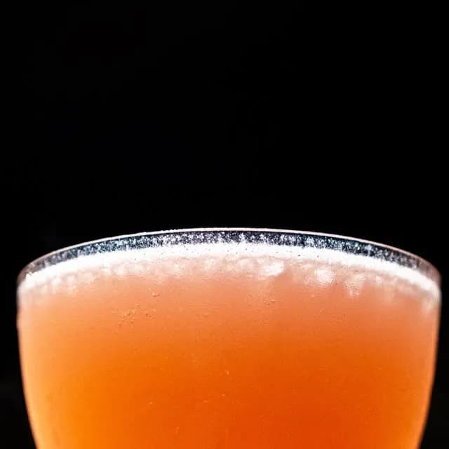Orange cocktail in a low-lit setting against a black background