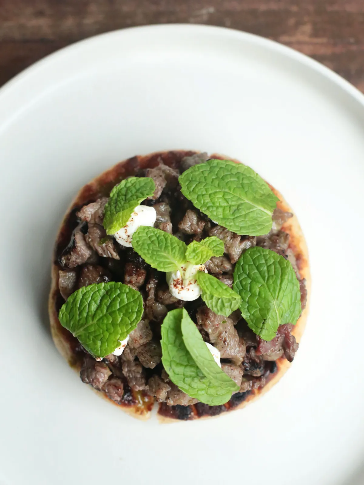Grilled beef flatbread topped with labneh and fresh mint