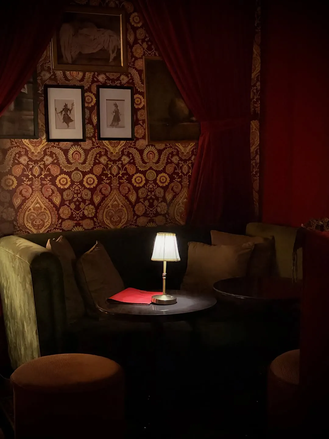 Dark red lounge with velvet sofas and a small table lamp