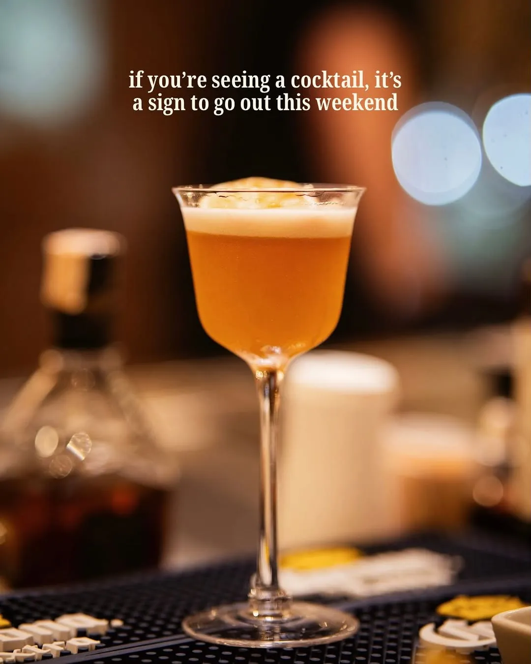 Cocktail in a coupe glass against blurred bar lights