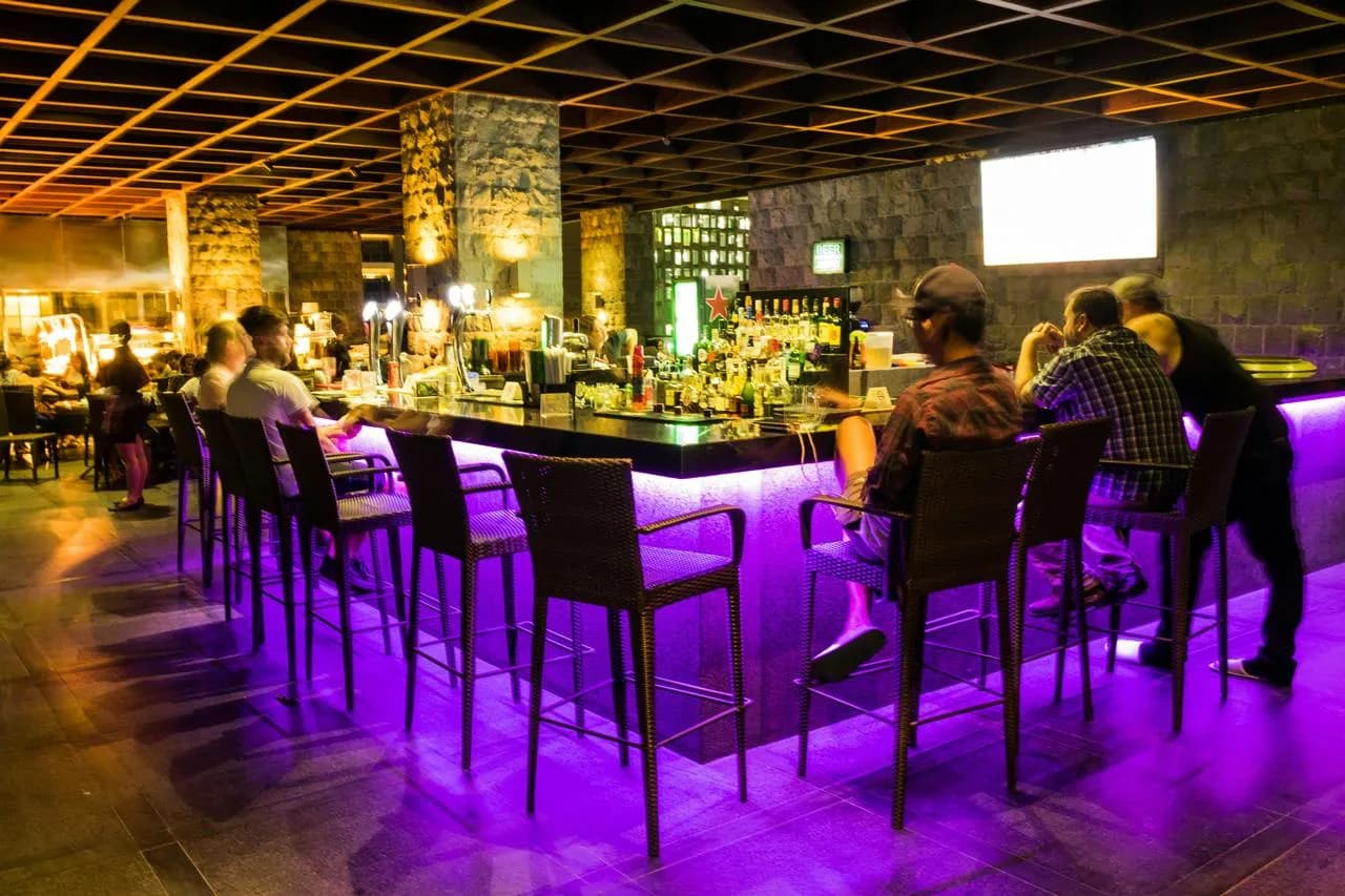 Firefly's illuminated bar counter with stools and bottle display at night