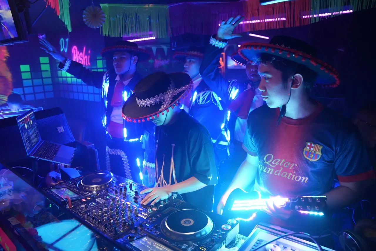 DJ and performers gathered around the illuminated booth.