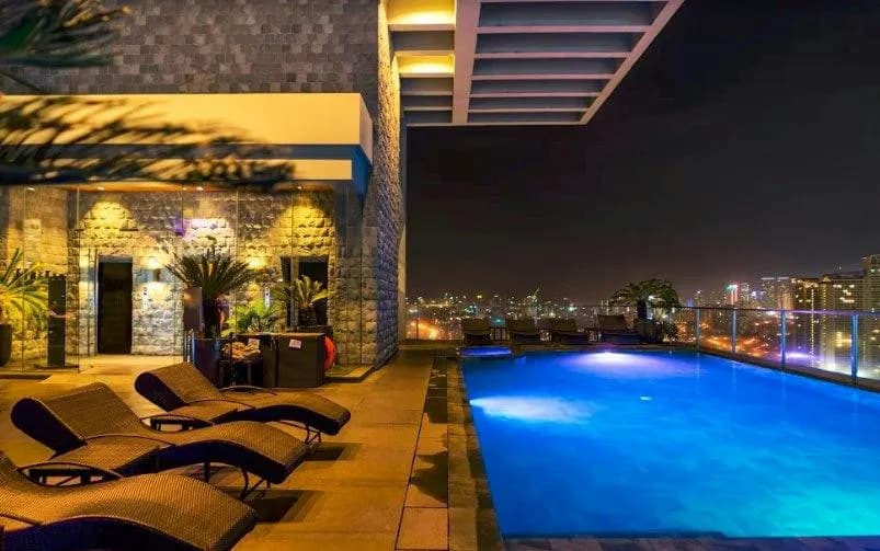 Blue-lit rooftop pool and Makati skyline after dark