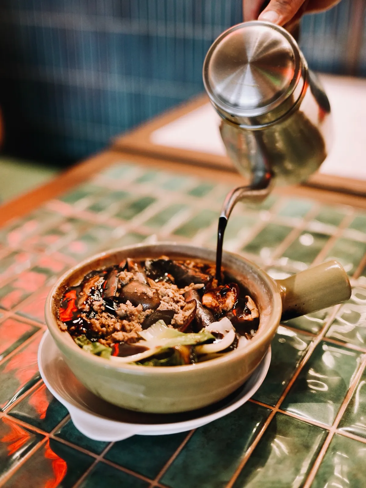 Claypot rice being finished with dark soy sauce at the table