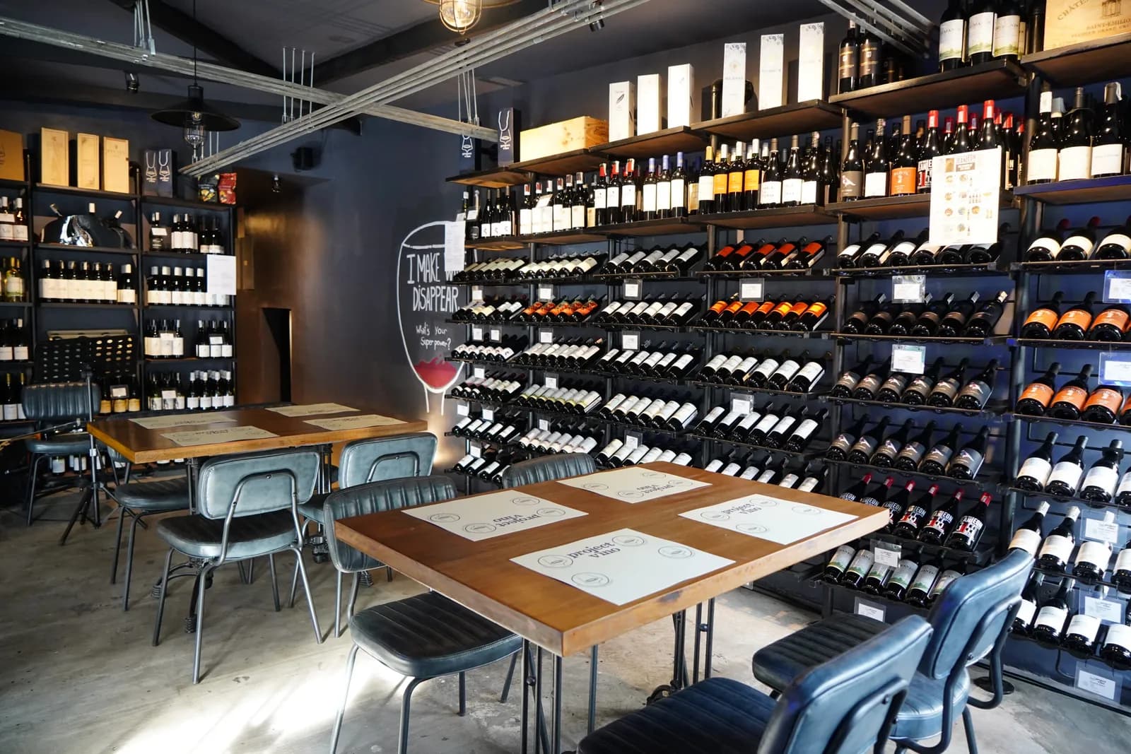 Dining tables and chairs beside wall-to-wall racks of wine bottles.