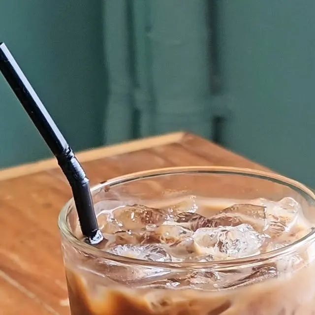 Glass of creamy Thai iced coffee on a wooden table