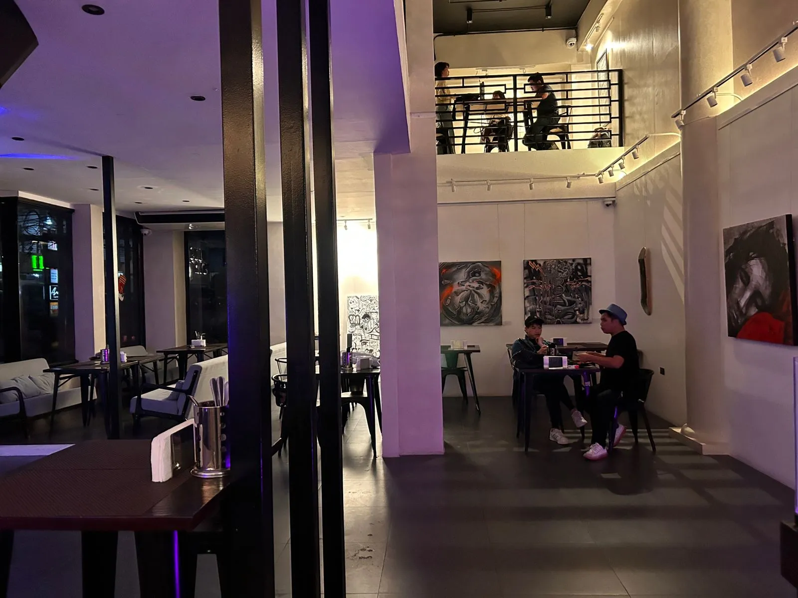 Art-lined dining room with tables under low evening light
