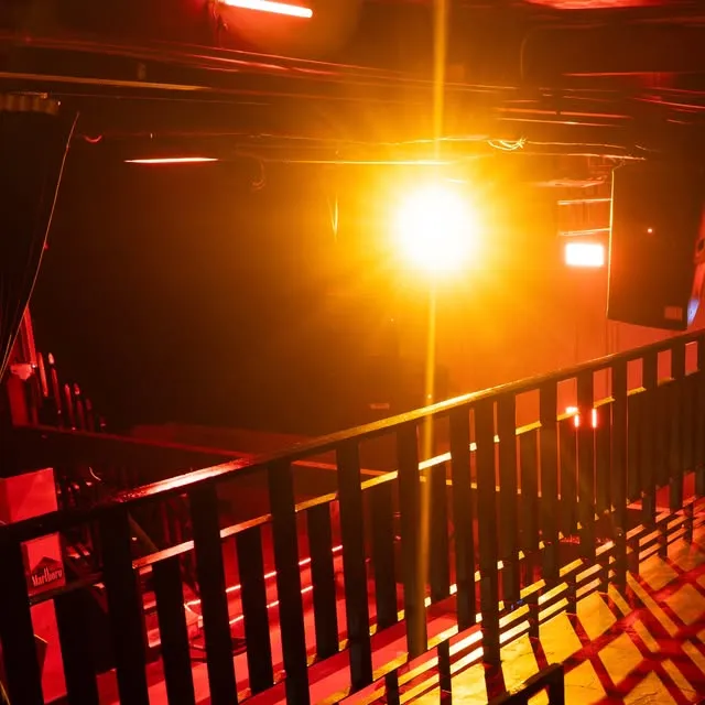 The club's black railings and lower level under intense amber and red stage lighting.