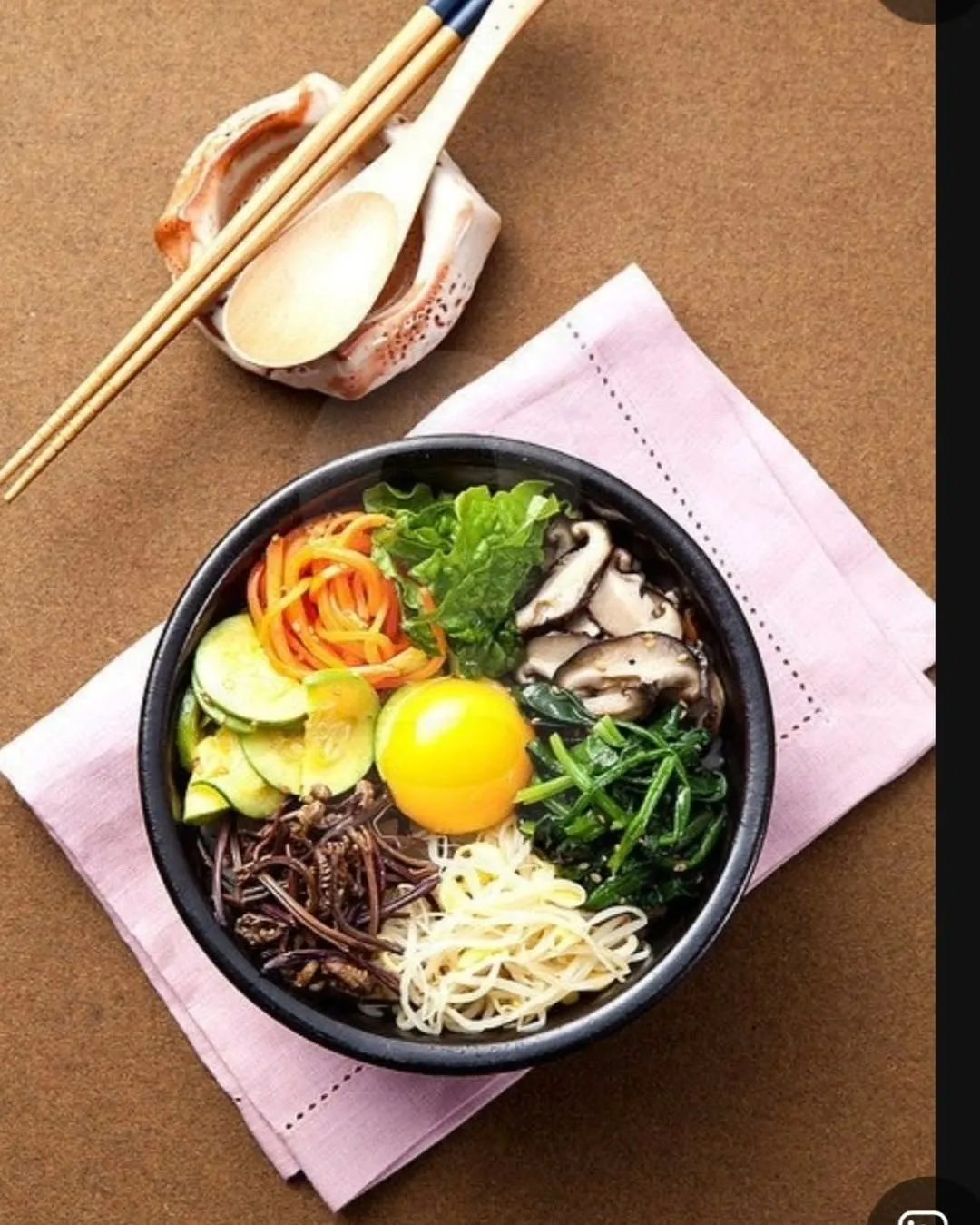 Stone-pot bibimbap topped with vegetables and egg yolk