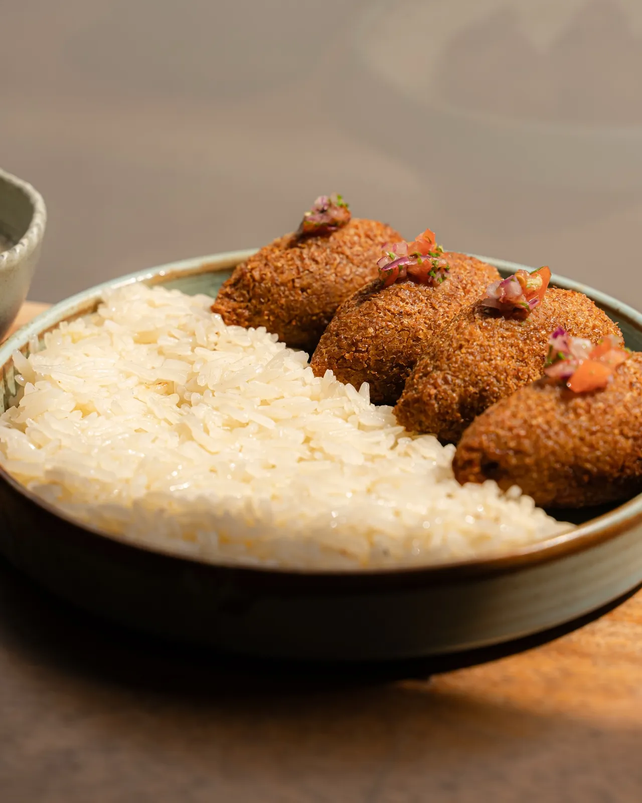 Kubbeh served over buttered rice with yoghurt sauce
